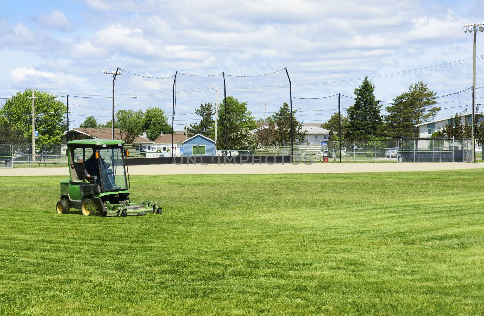 Small tractor cutting the grass of the baseball playing field before the game.