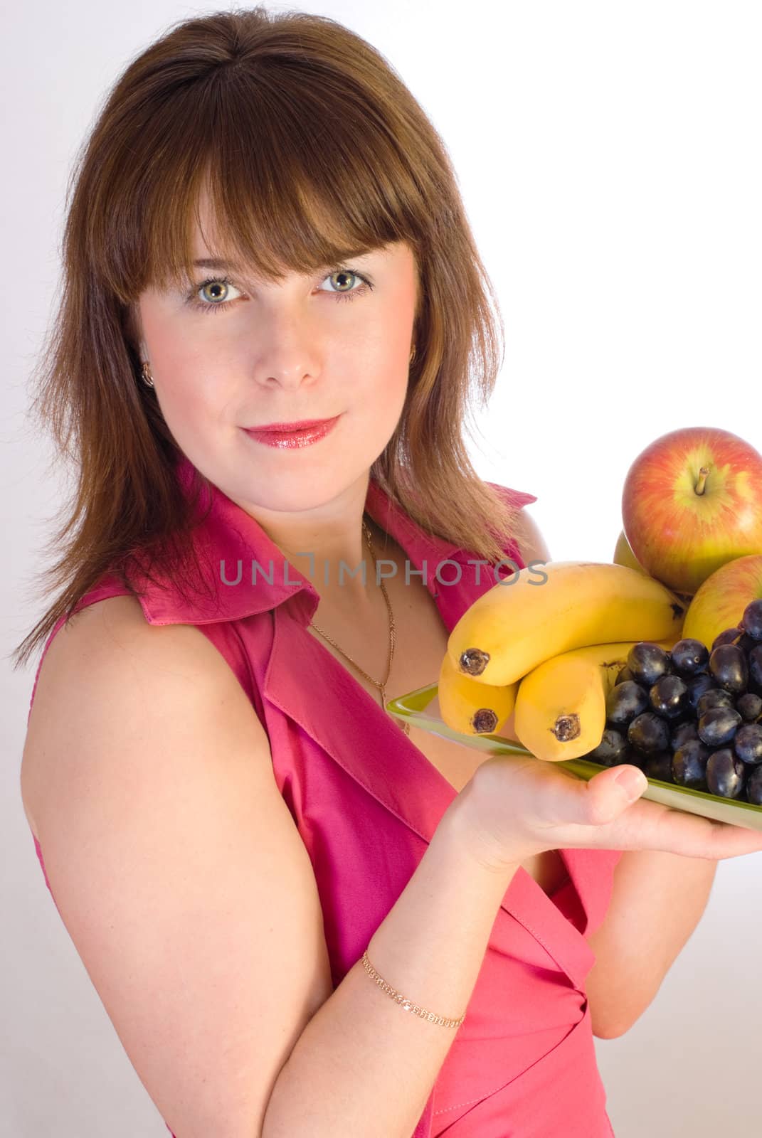 beautiful smiling girl with dish of fruits on grey background