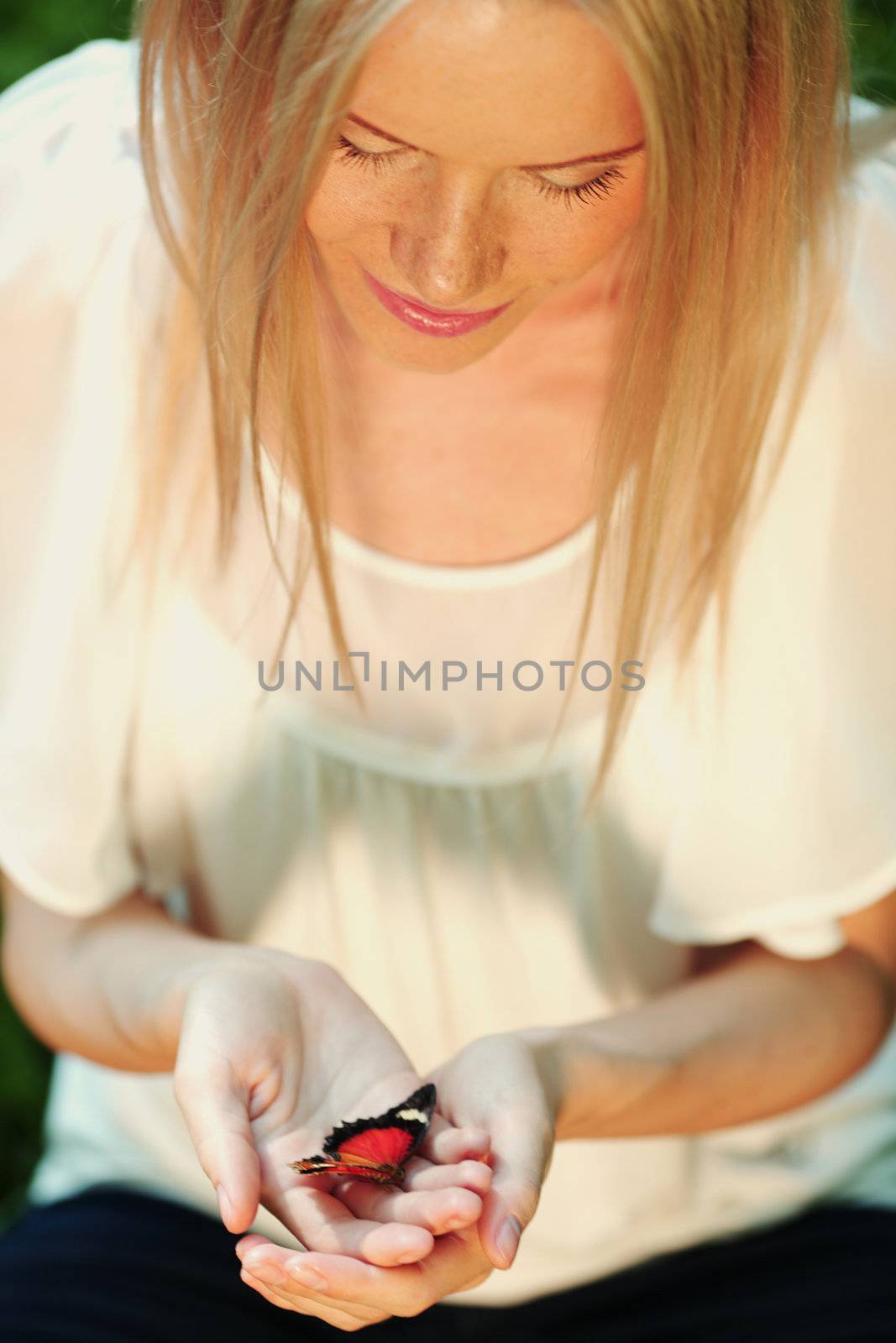 Woman playing with a butterfly on green grass