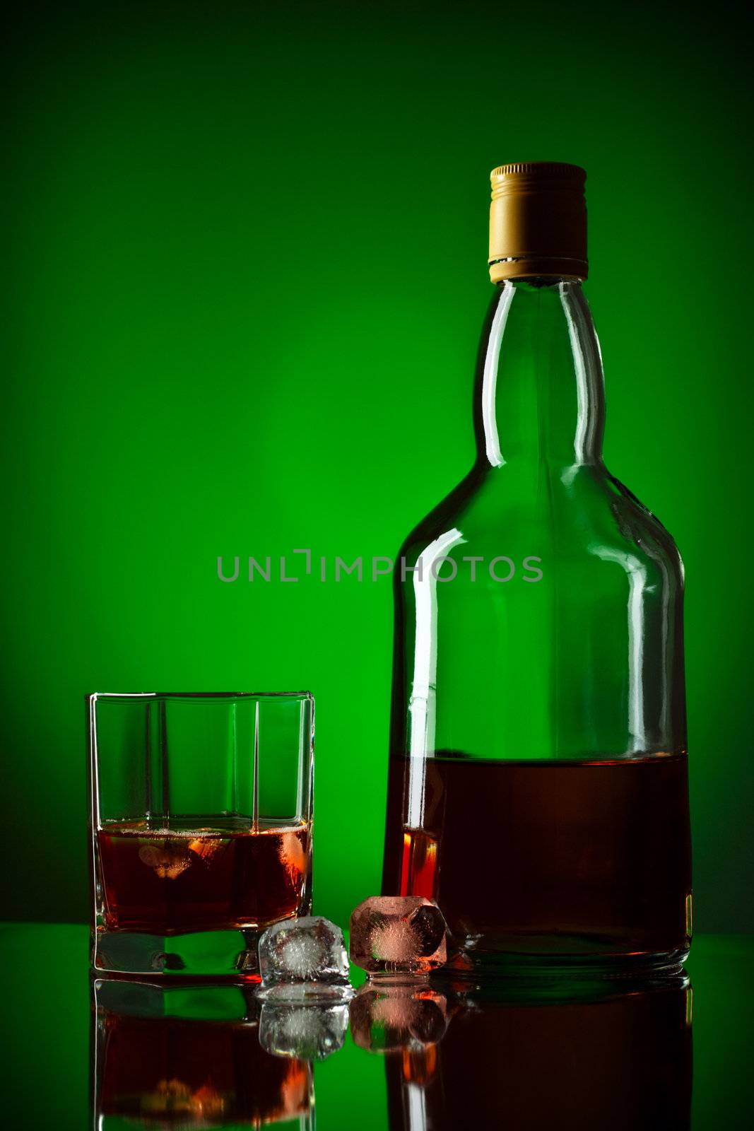 whiskey bottle, ice and glass, green background