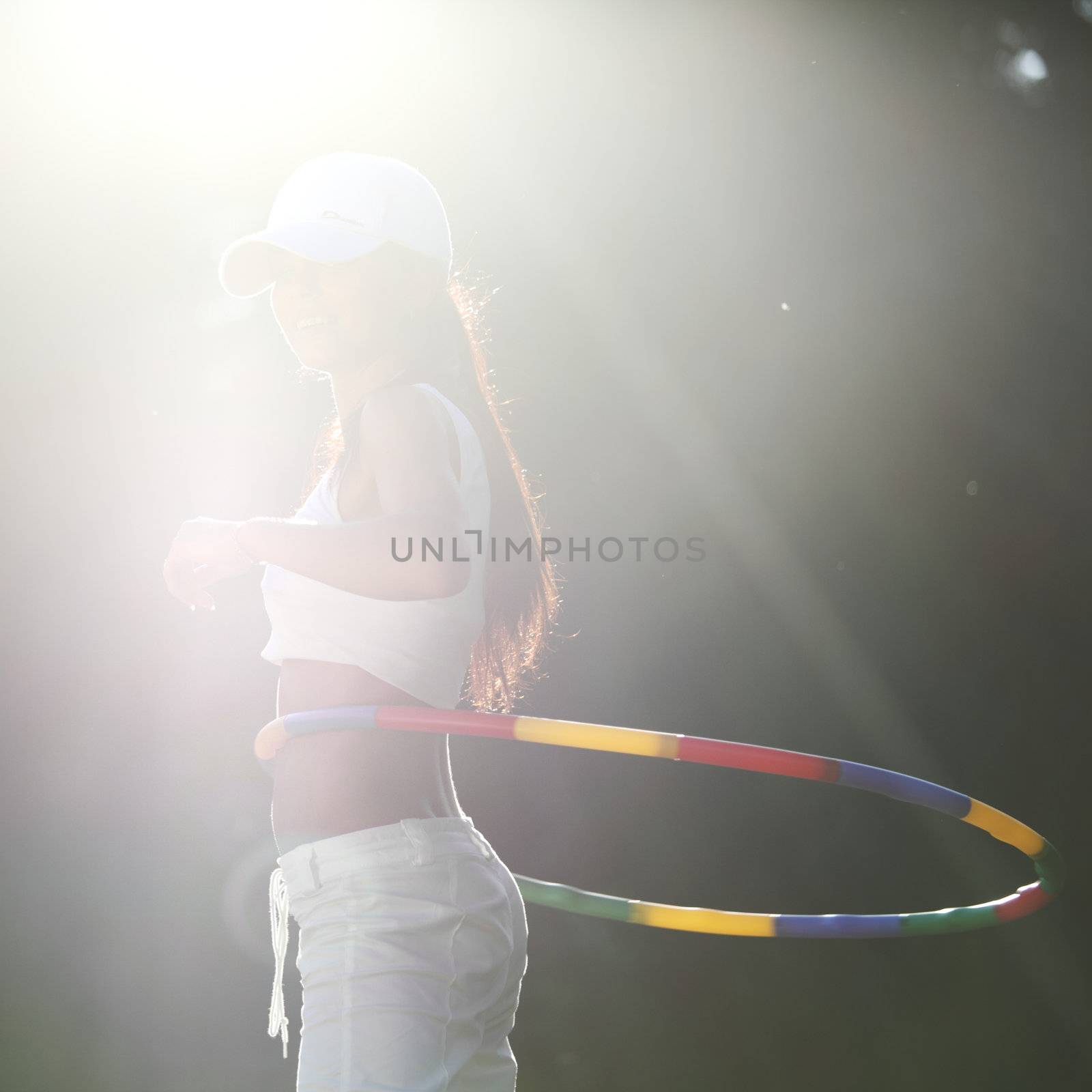 woman rotates hula hoop on nature background