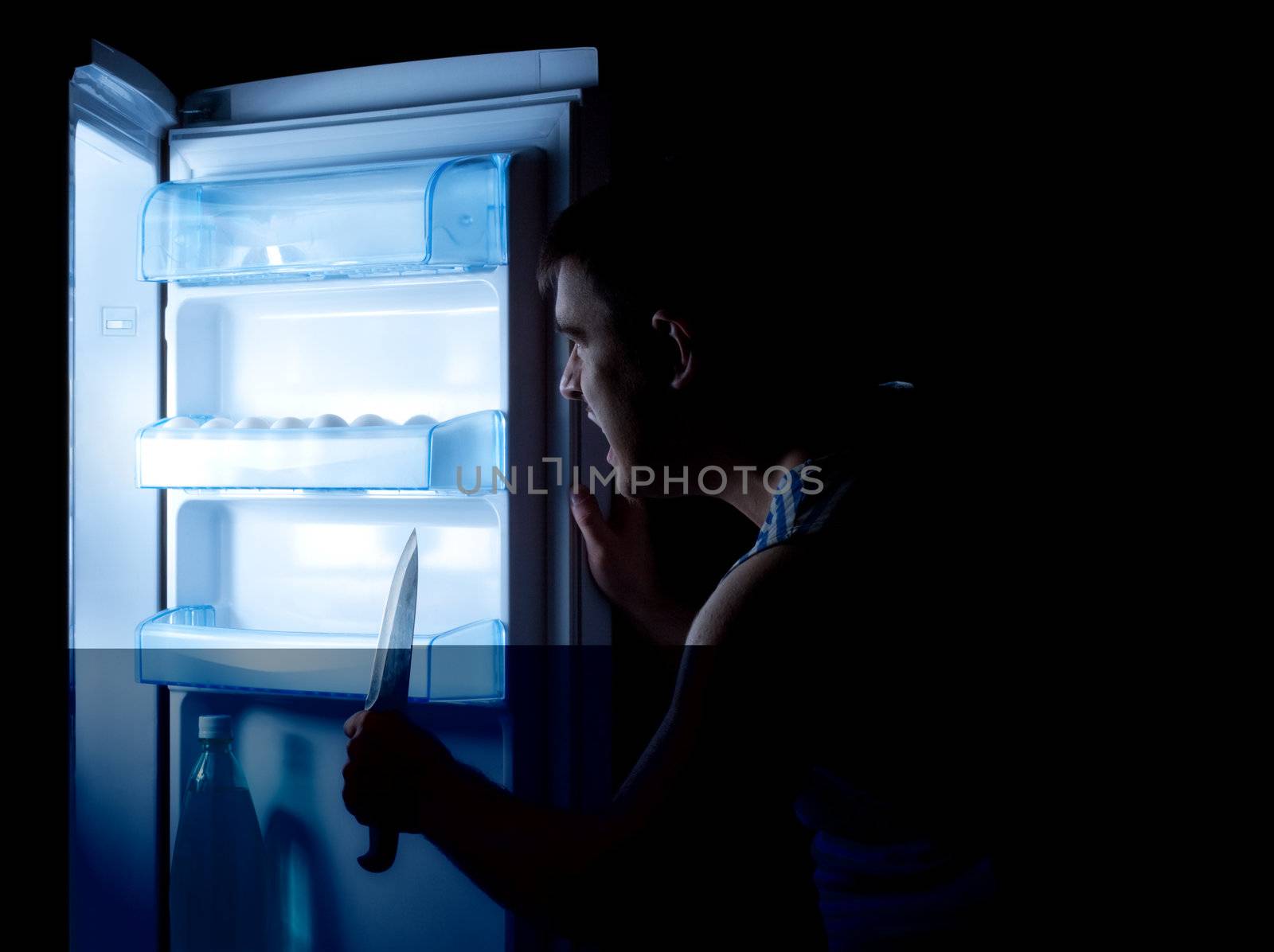 man with knife opening refrigerator door and sees something terrible