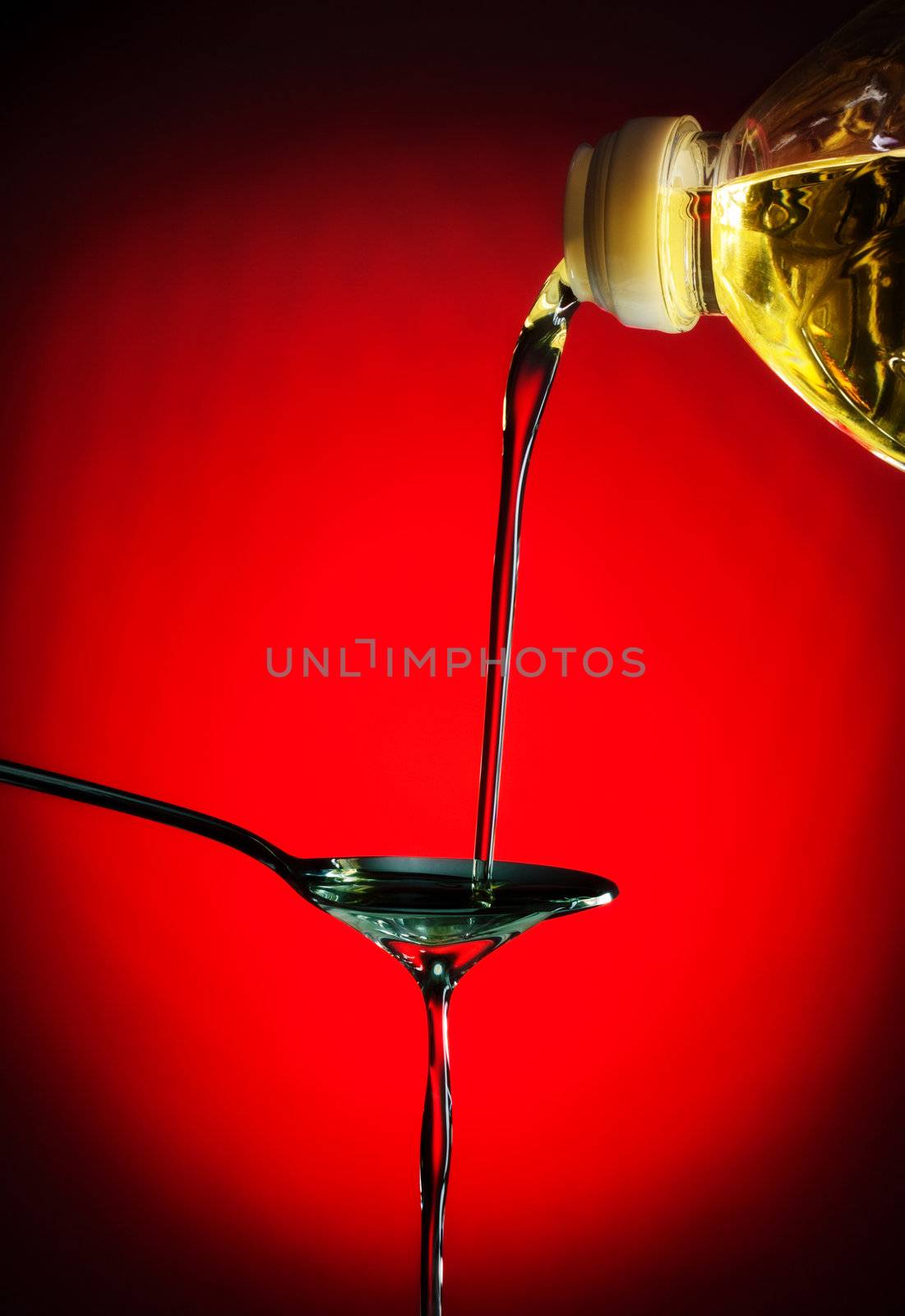 pouring oil on spoon, red background