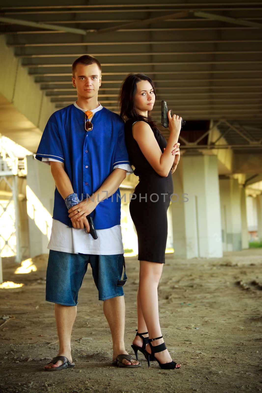 young couple with guns under bridge