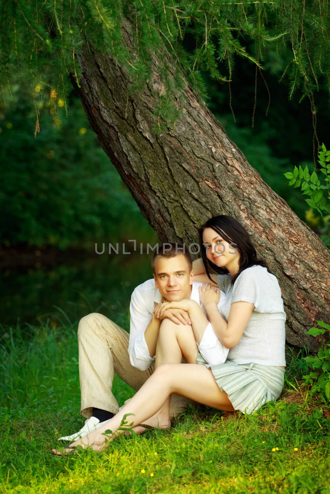 young couple sitting under tree by petr_malyshev