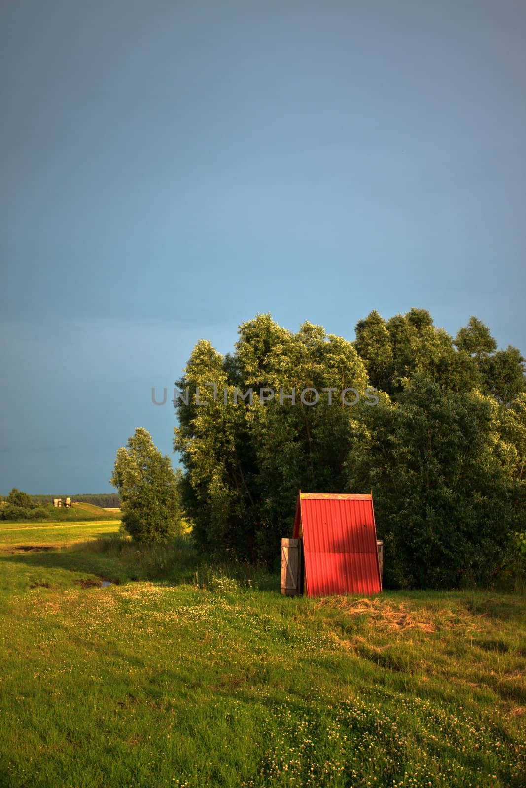 wooden cabin on meadow at evening