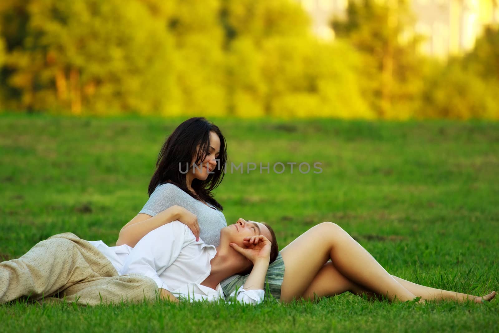 young couple laying on park lawn