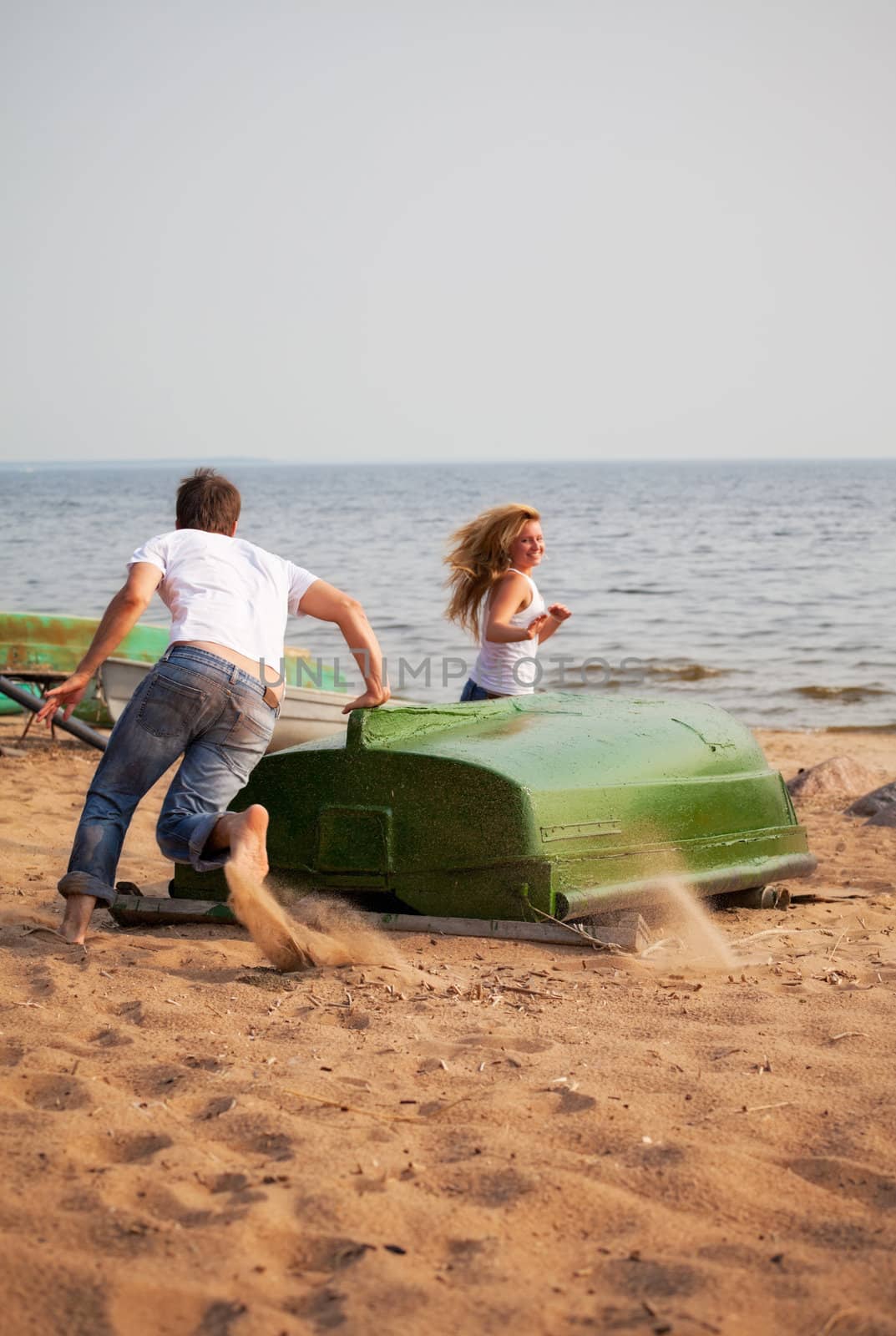 young couple fun and run around old boat on a beach