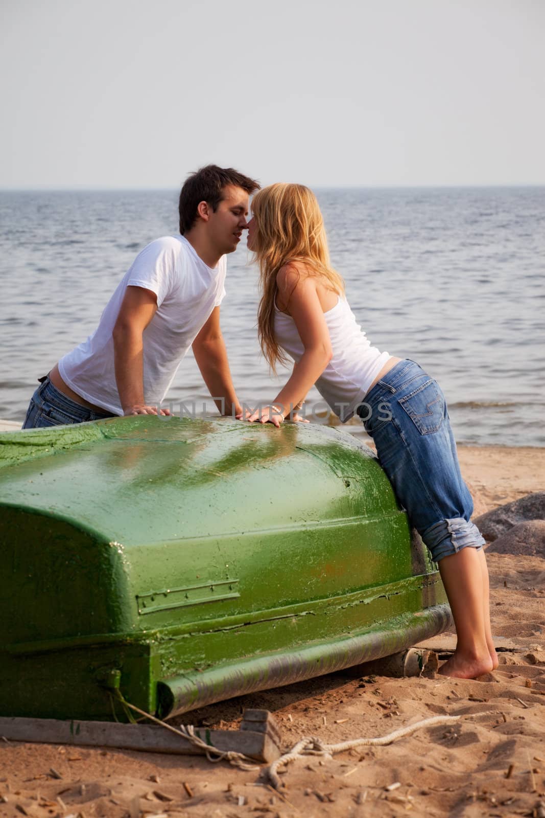 beautiful couple kissing on a beach near old boat