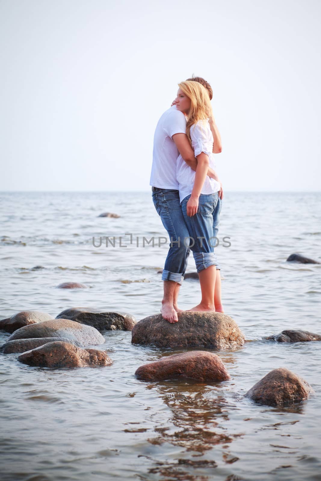 couple embrace on a big stone in sea