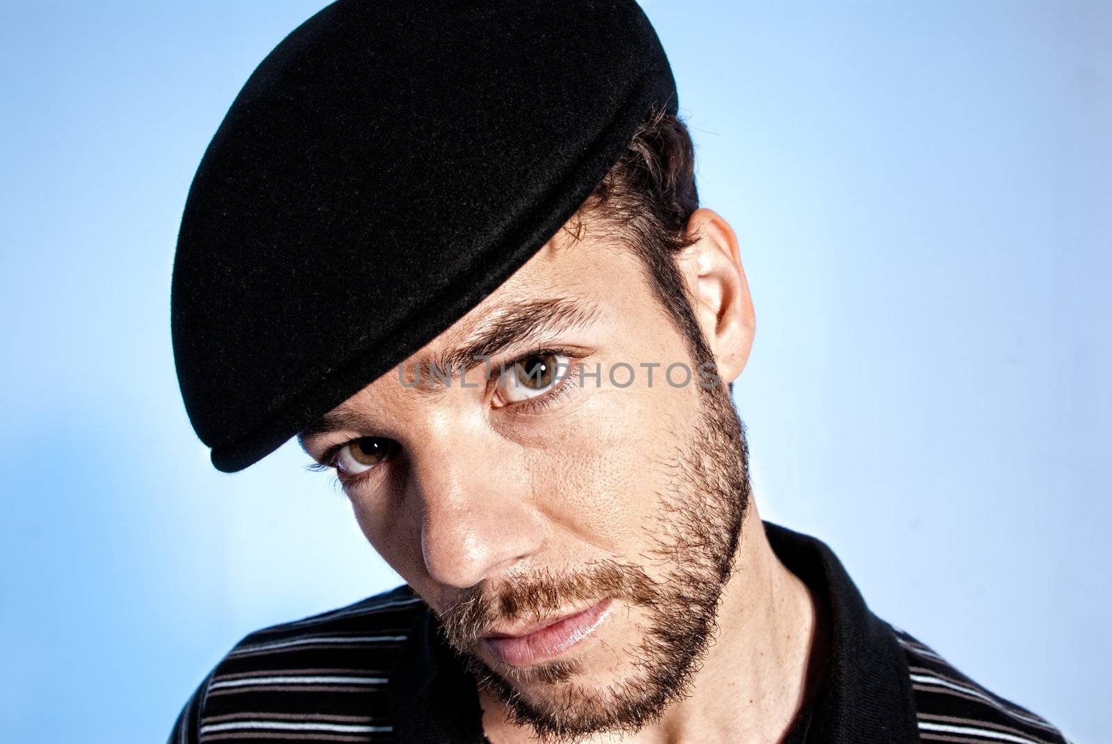 Young modern handsome man portrait with hat on blue background