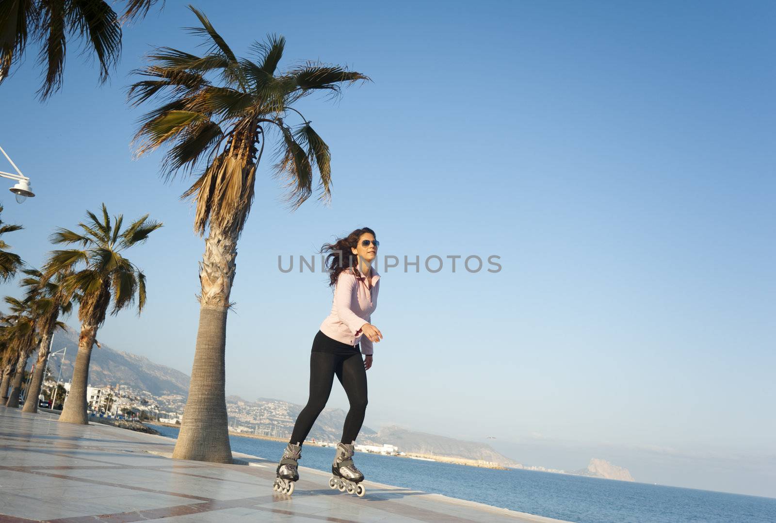 Woman skating along a sunny Mediterranean beach