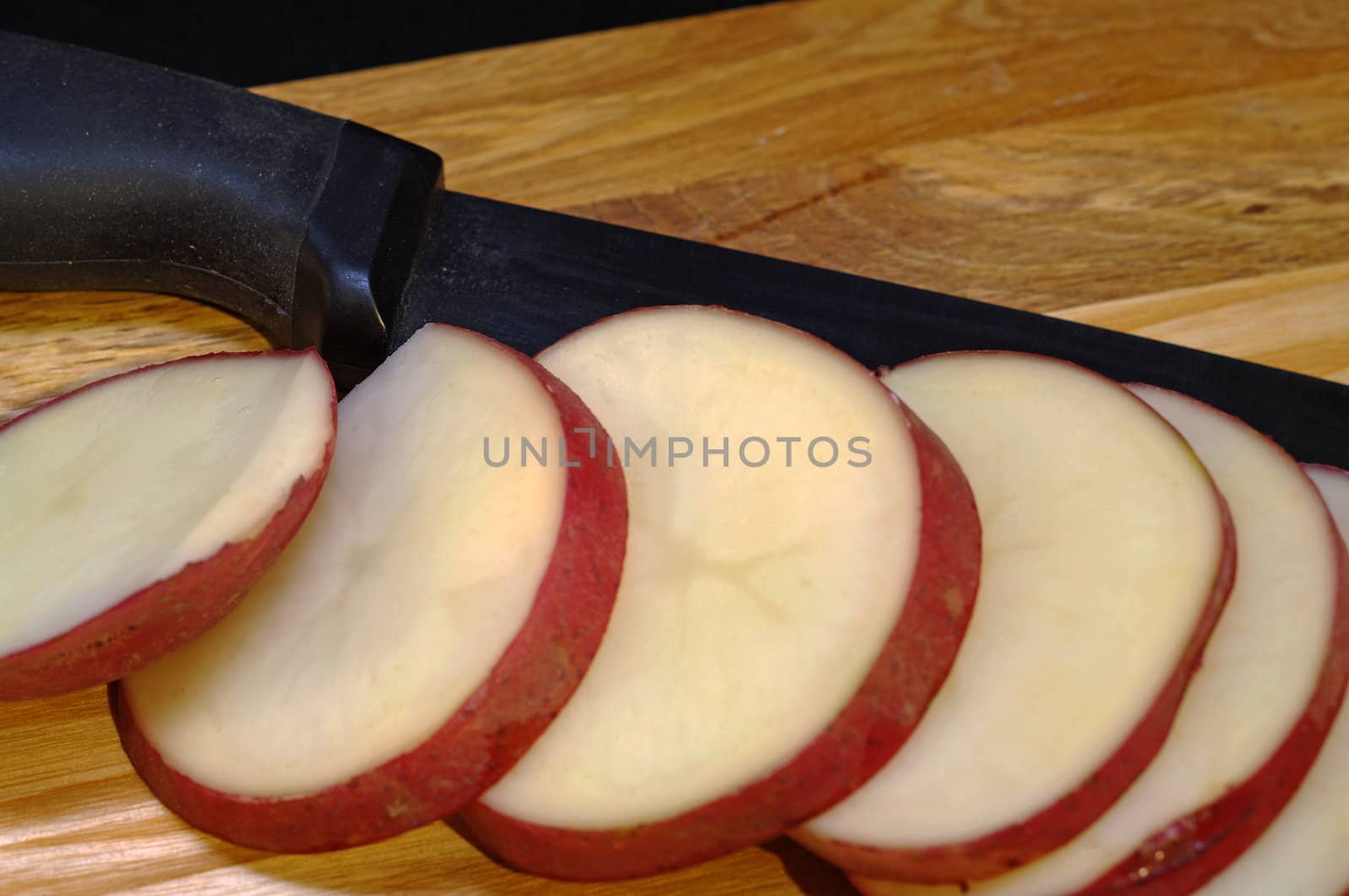 Red potatoes being sliced on a cutting board