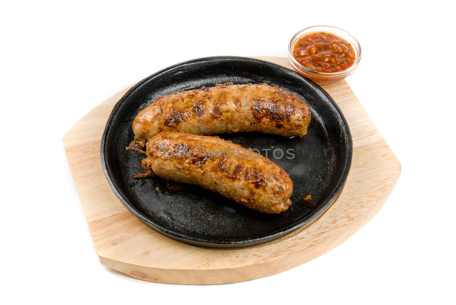 Roasted sausages at pan with sauce on a white background