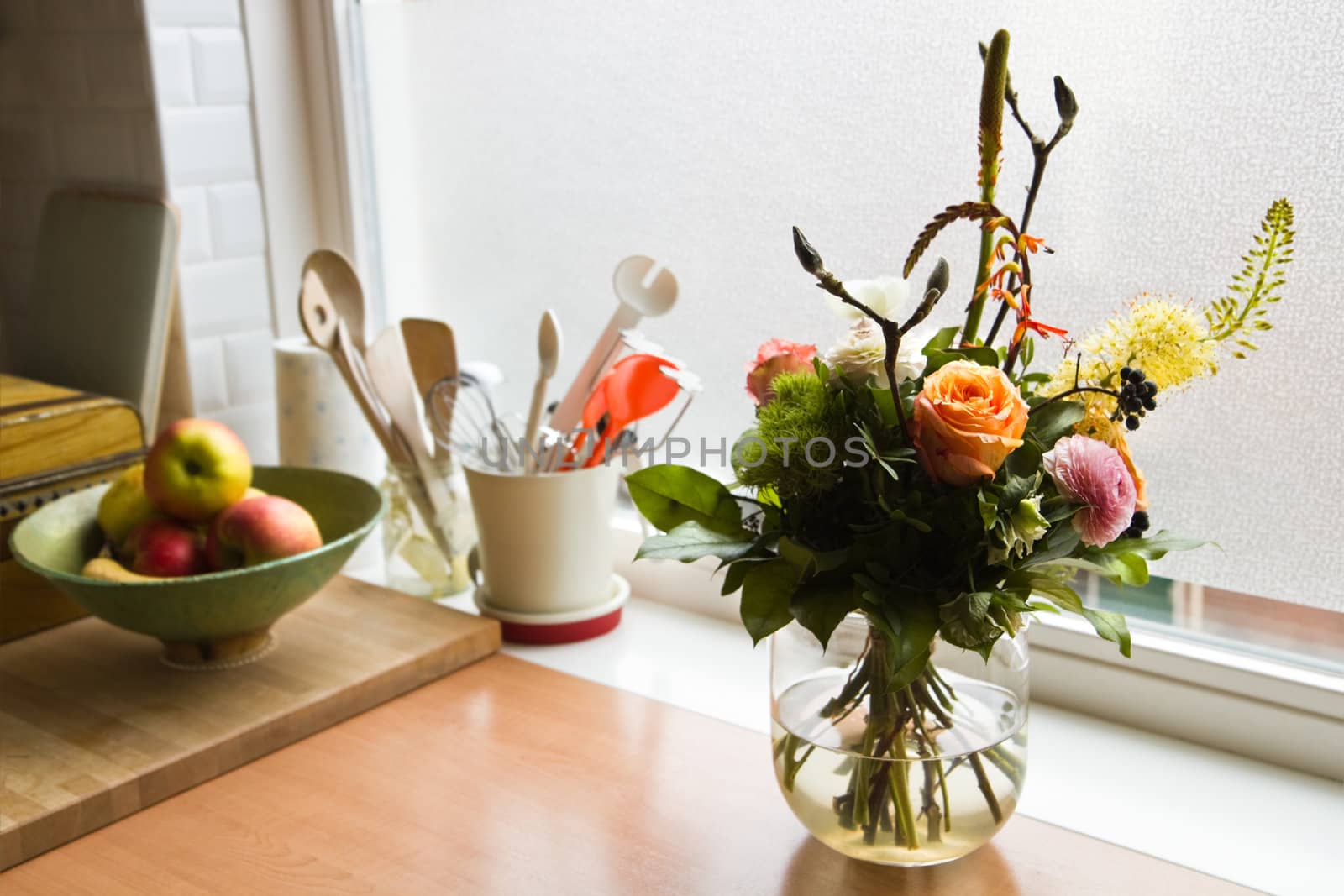 Bouquet of flowers on dresser in modern kitchen with window in background