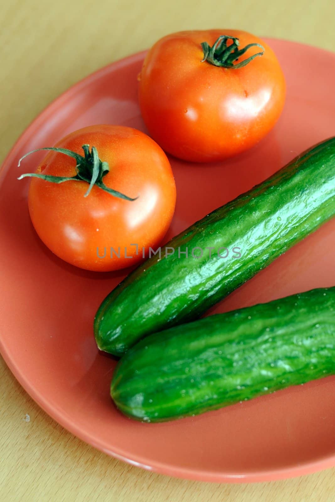 An image of tomatoes with cucumbers on plate