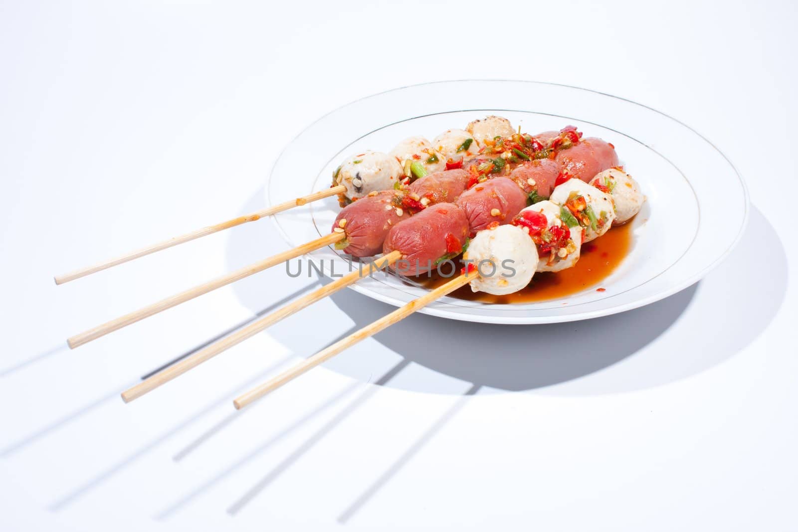 Pour sauce meatball skewers grill plate on a white background.