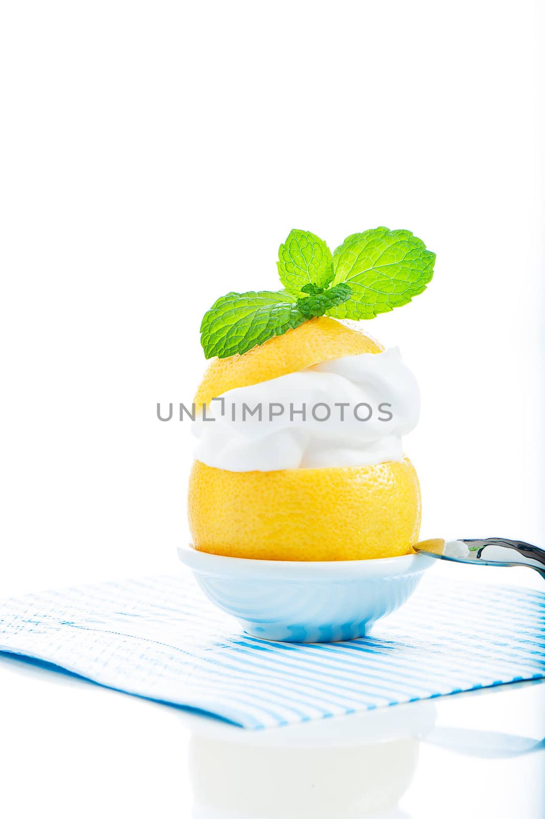 A fresh lemon with lemon cream and mint on the top on white background as a studio shot