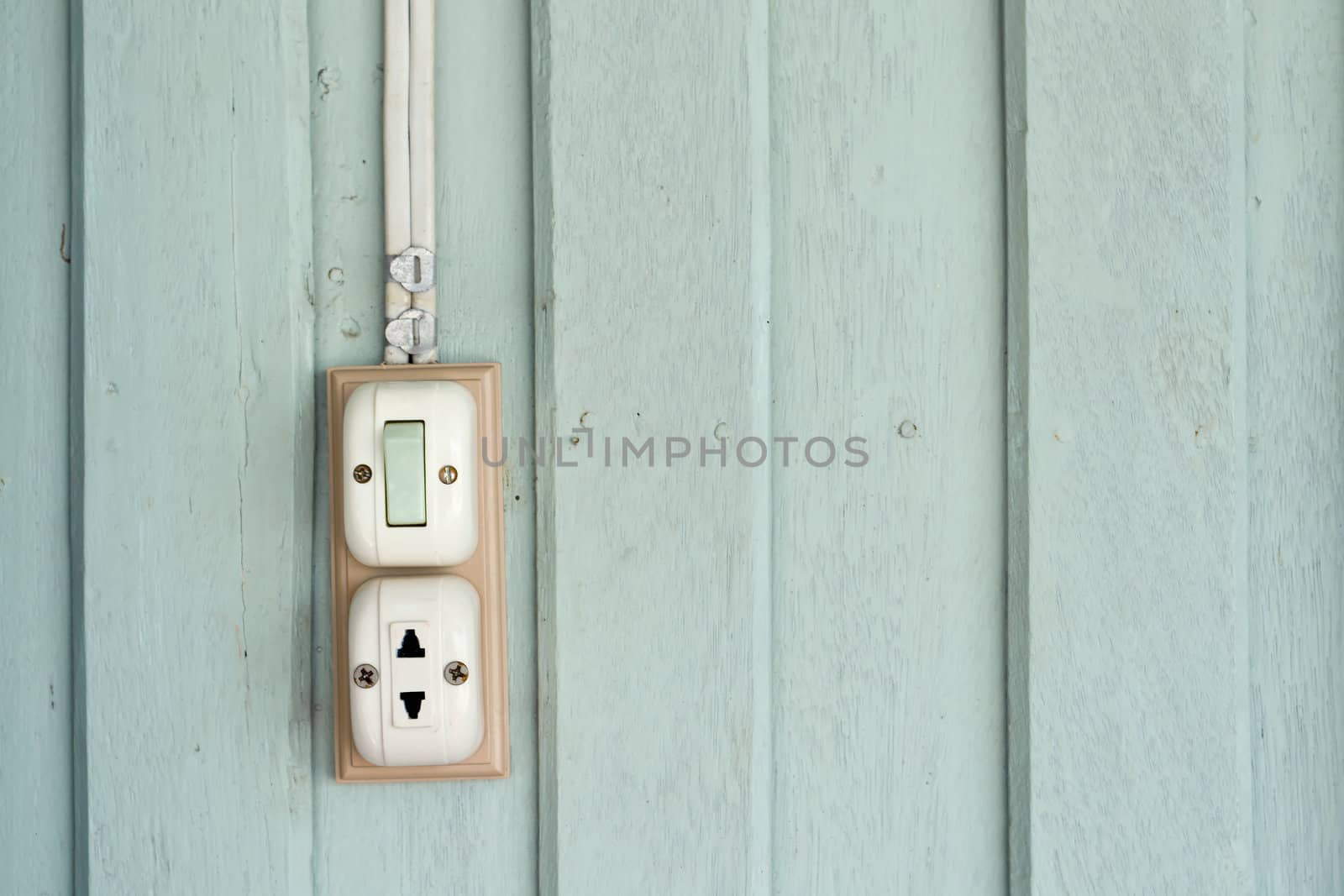 Switch and power outlet on green wood wall