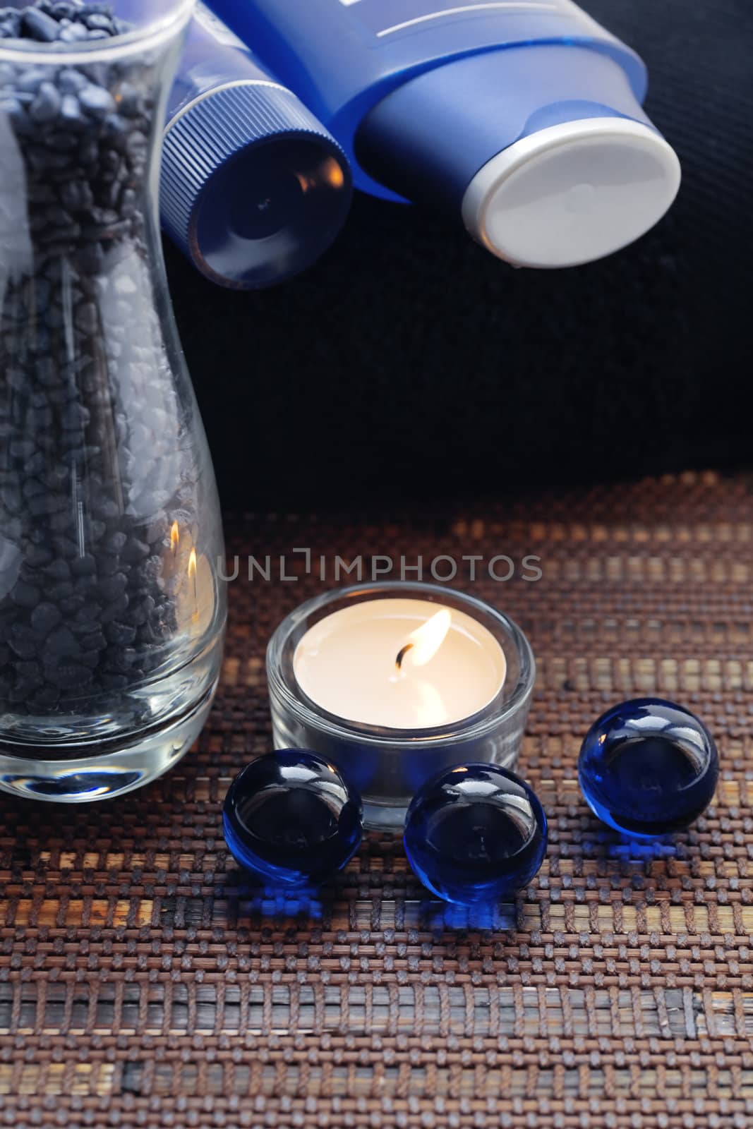 Creams for body care, candle and a blue pebble for spa treatment