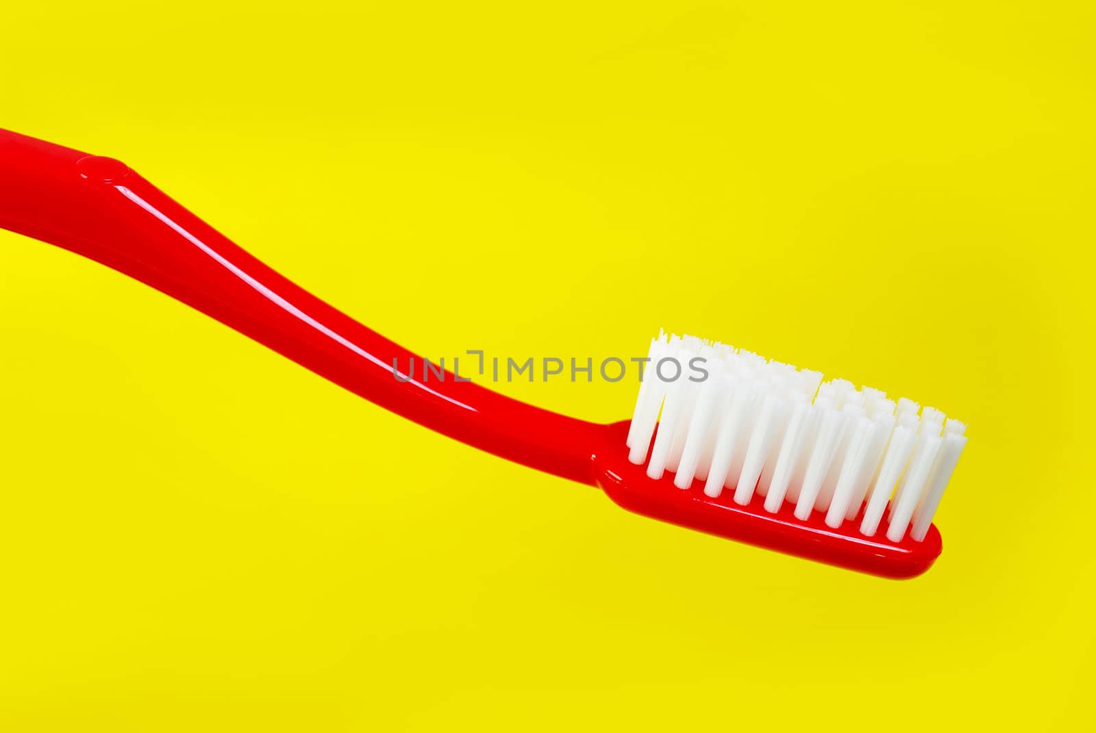 Red toothbrush on yellow background 