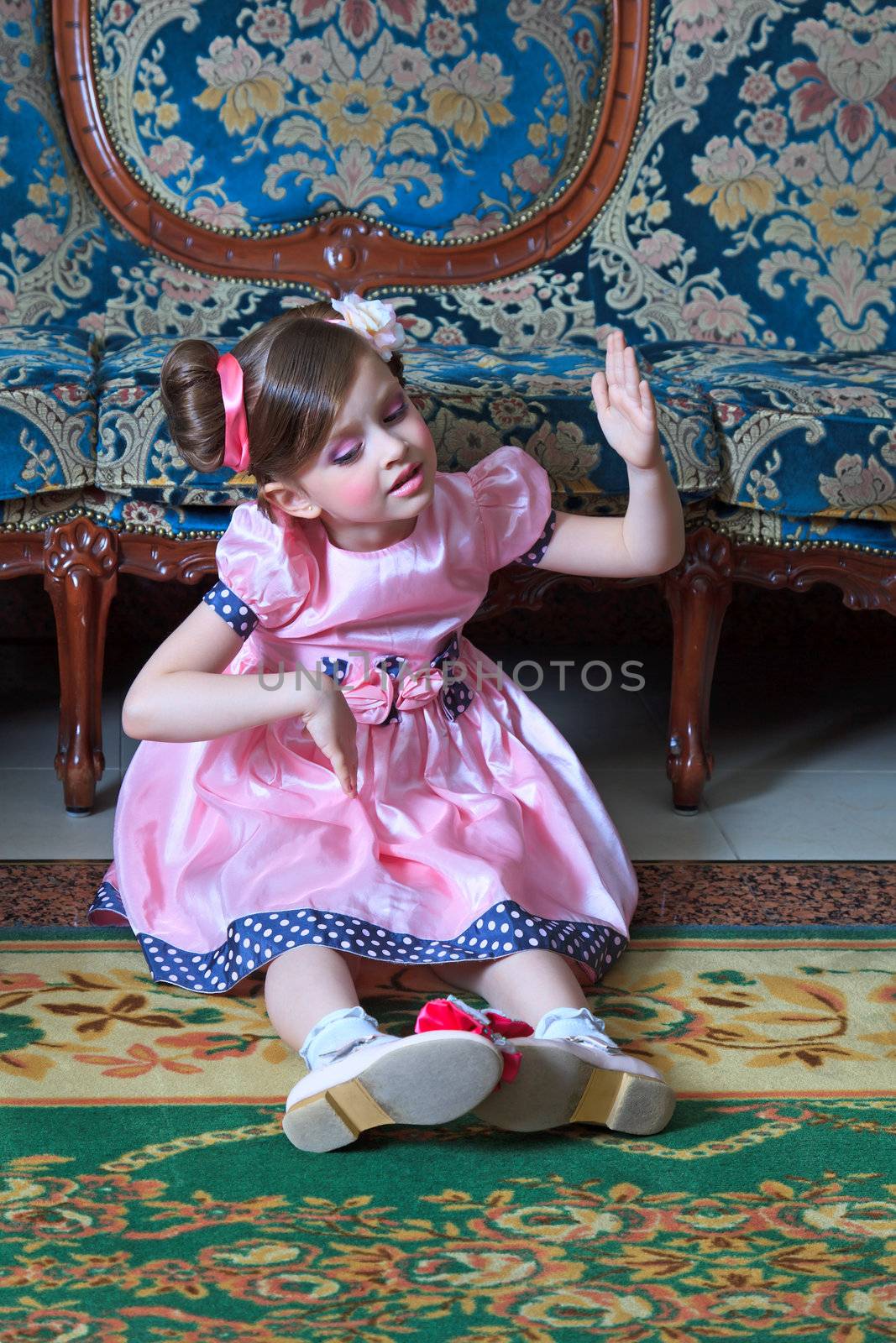 The girl in pink, sitting on the floor depicts a doll.