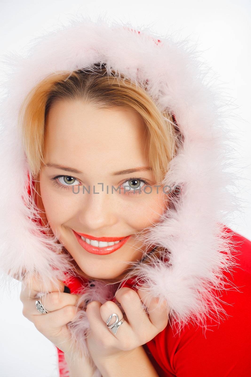 Smiling young girl posing in a winter cap and knit sweater. Studio portrait on white background