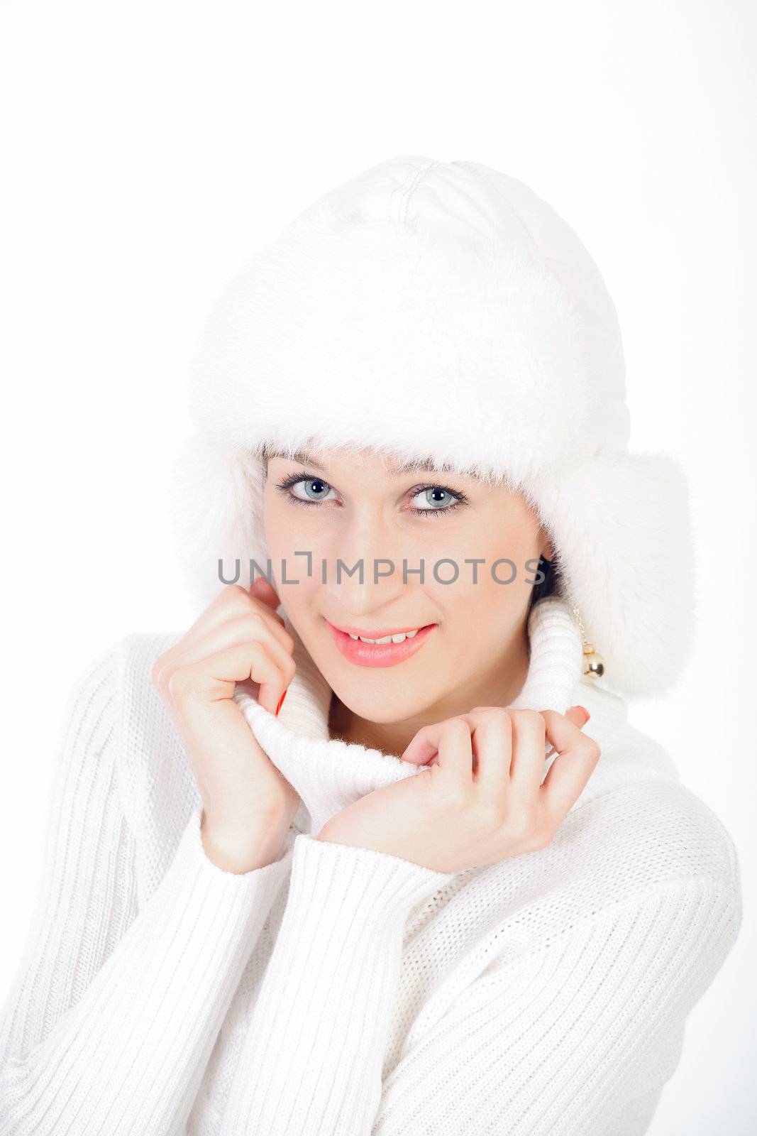Smiling young girl posing in a winter cap and knit sweater. Studio portrait on white background