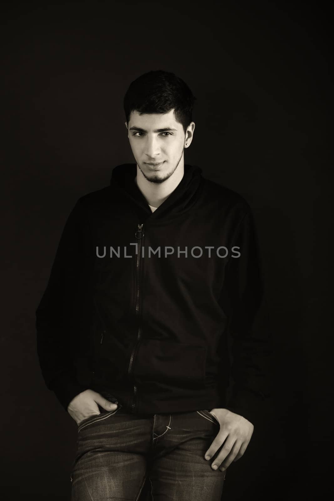 Portrait of a young man in the studio. Black - White. Toned, hard light is applied to achieve an artistic effect.