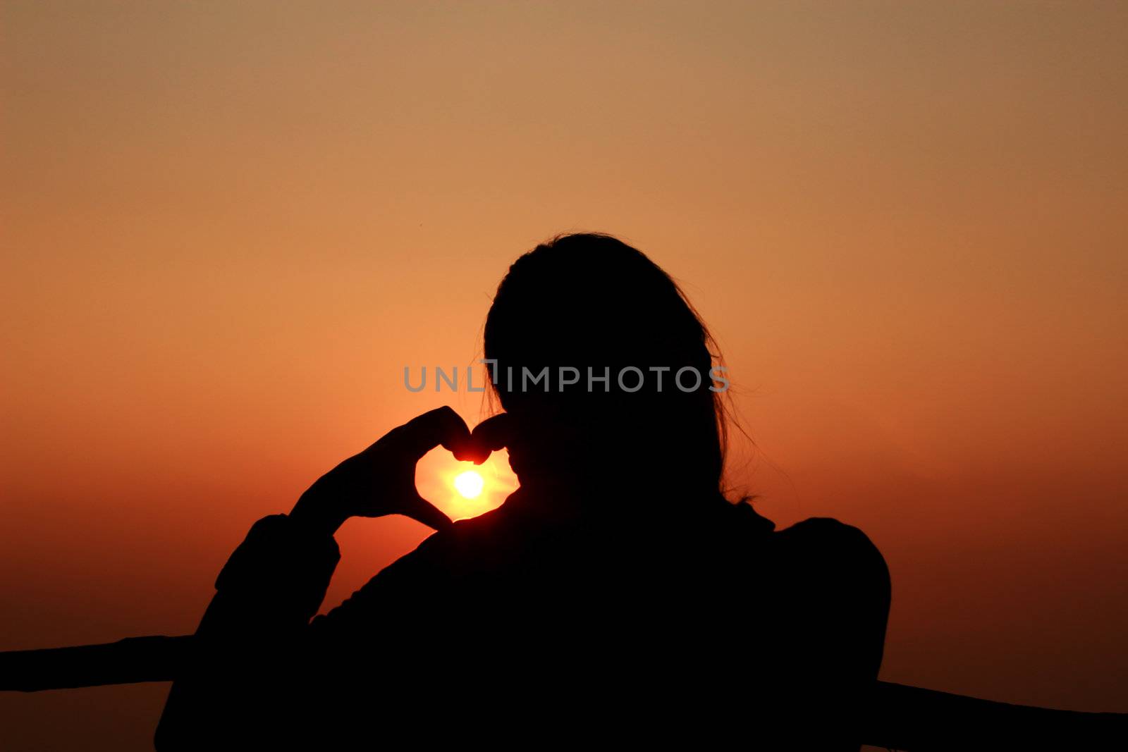 Hands make heart shape before Sunrise .