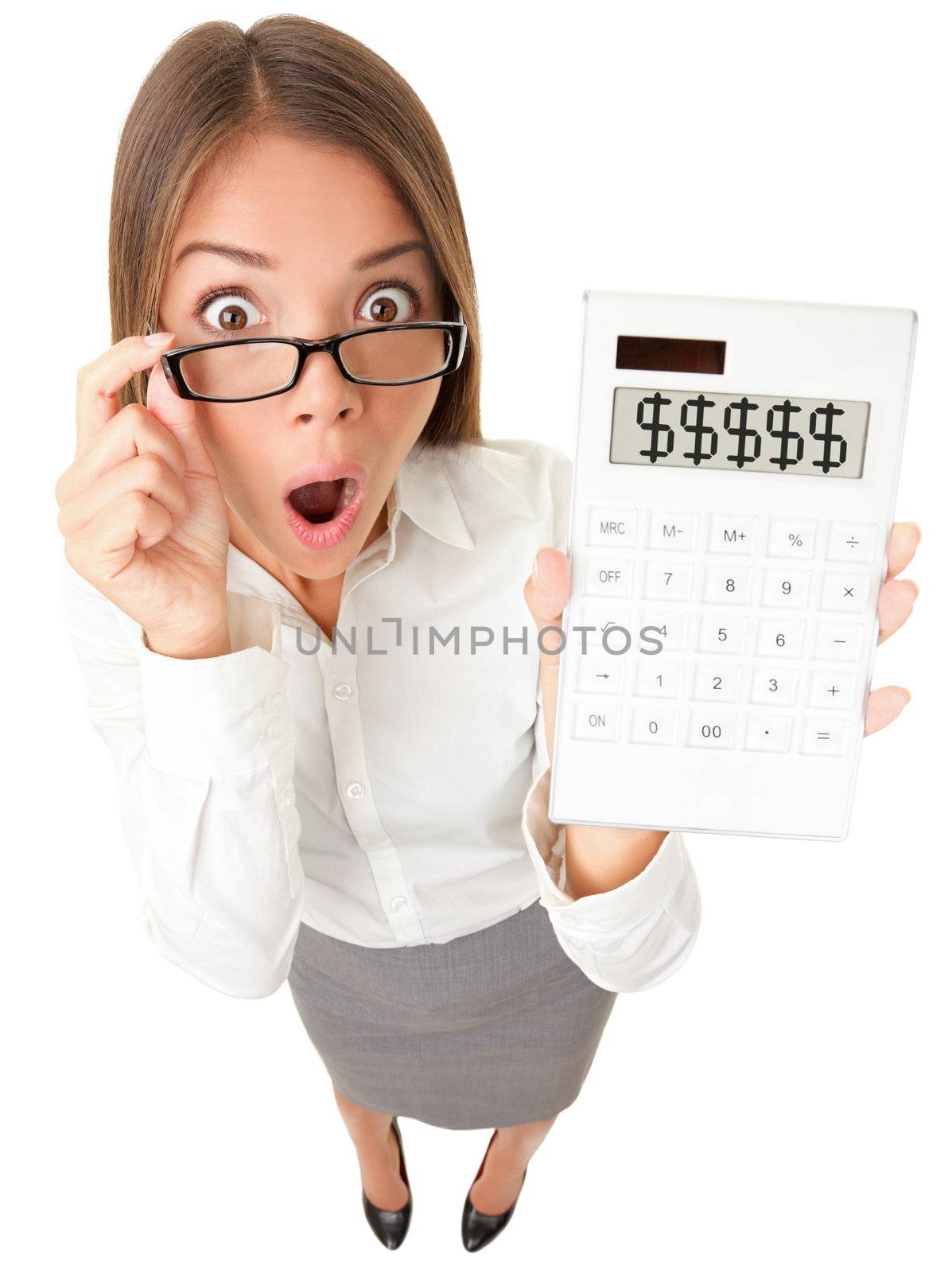 Business woman accountant shocked showing dollar signs on calculator. Surplus, debt or financial crisis concept image. Funny surprised young woman isolated on white background in high angle view.