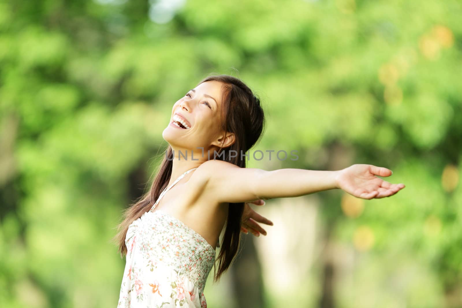 Happy woman in spring / summer smiling carefree and joyful in summer dress in beautiful park. Aspirational freedom concept with beautiful mixed race asian / caucasian girl
