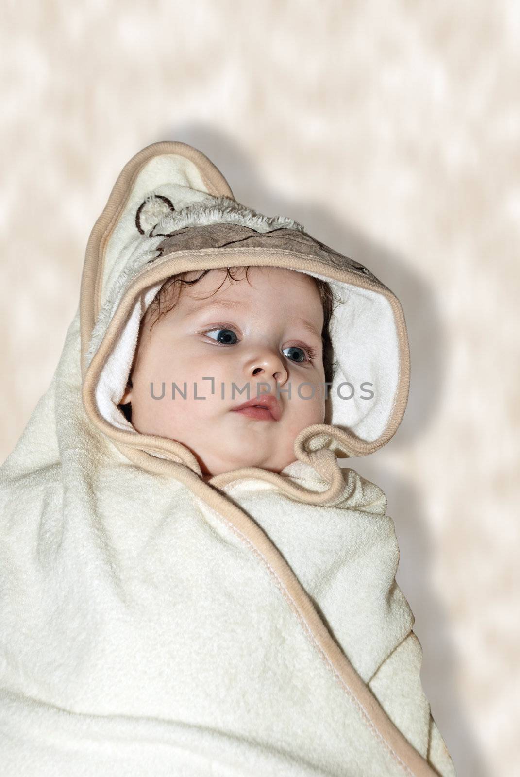 Beautiful baby wrapped in a brown blanket after bath