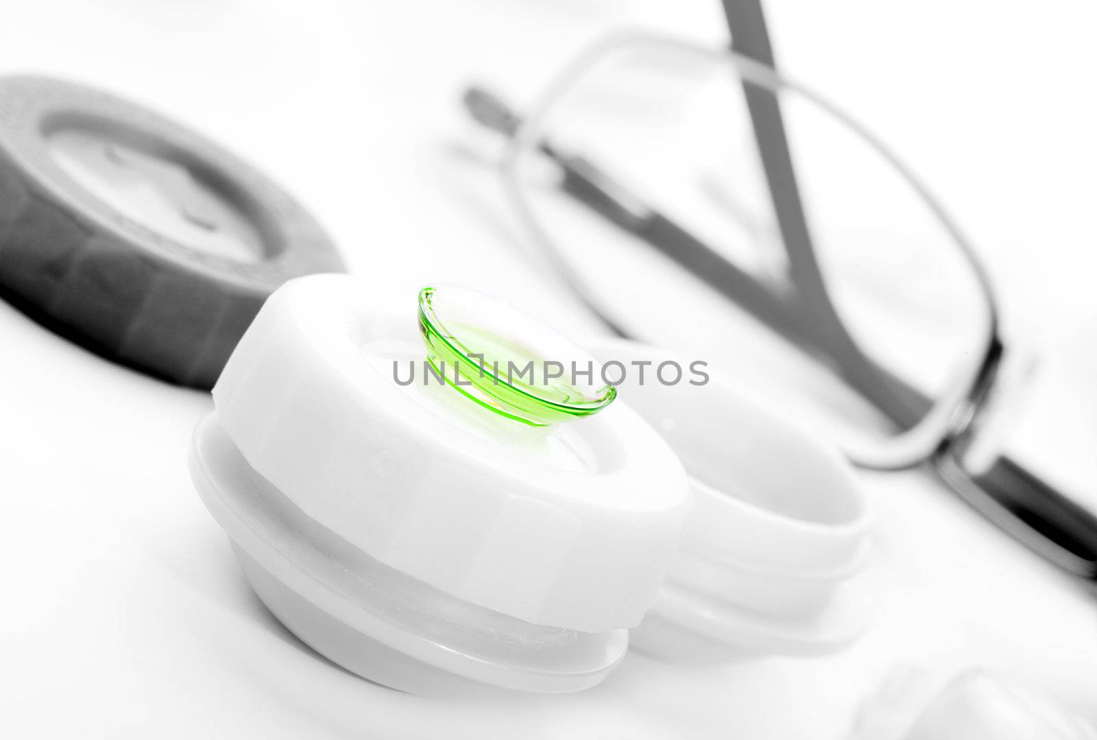 Close-up of green contact lenses in container with solution.  by motorolka