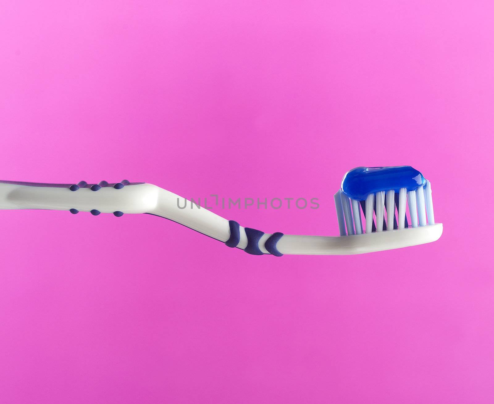 Toothbrush with toothpaste on pink background