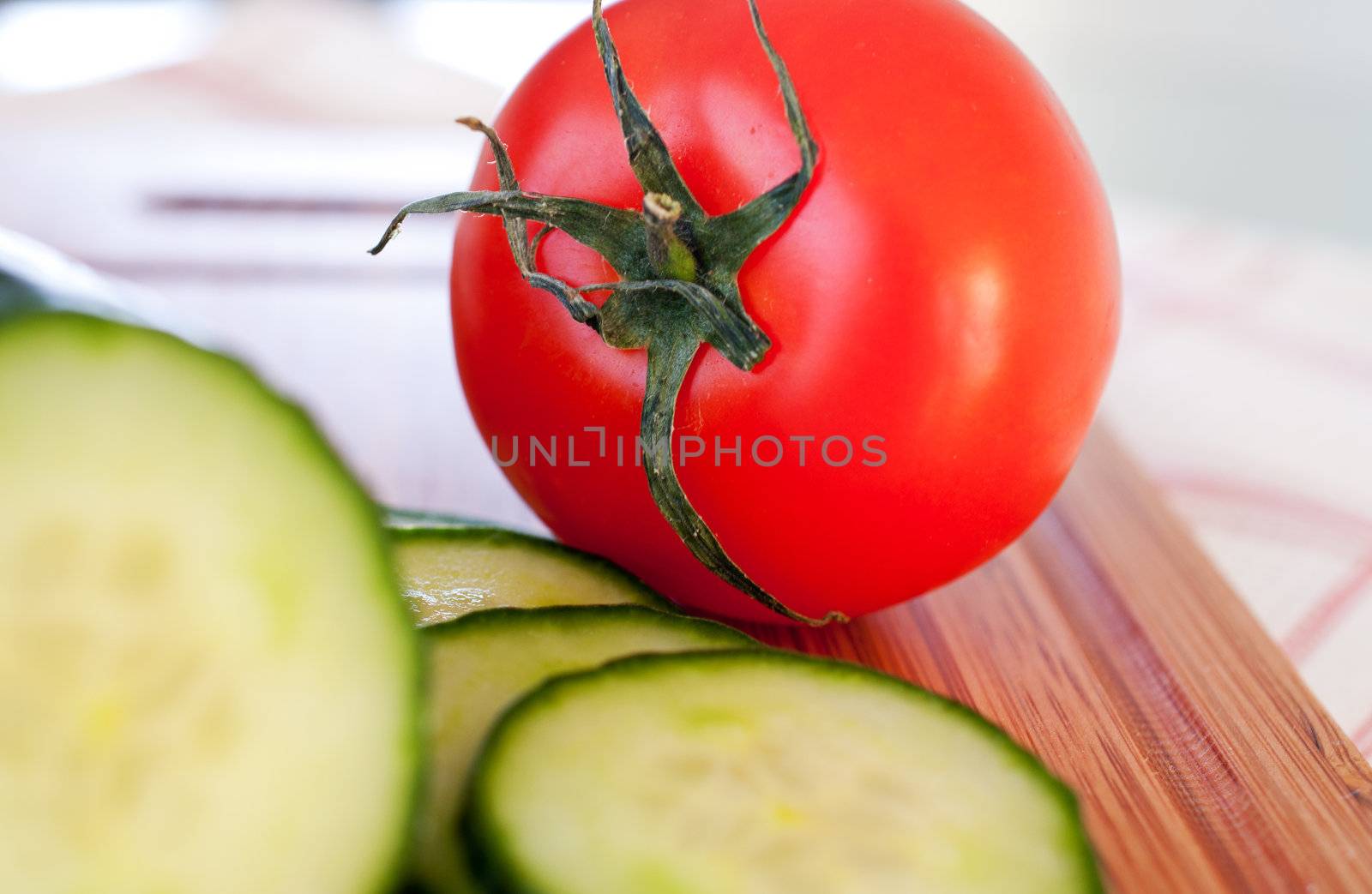 Tomatoes and cucumbers on wooden board close up