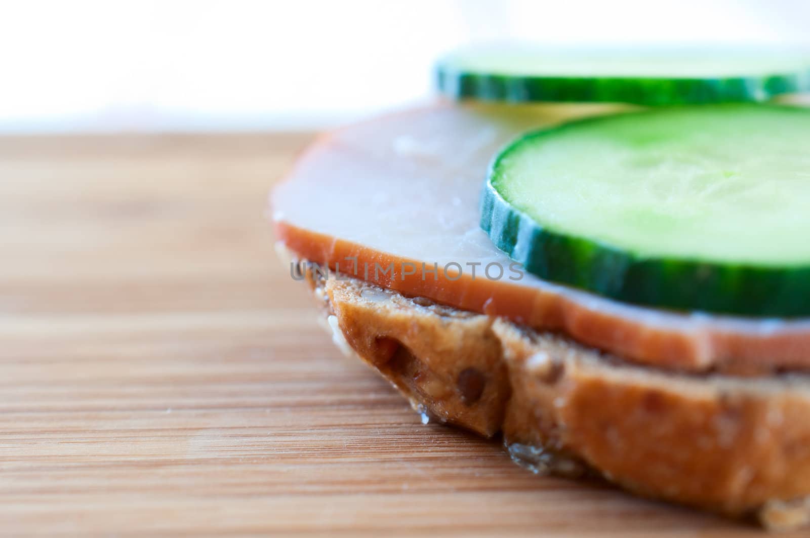 Sandwich with ham and cucumber on a wooden board  by Nanisimova