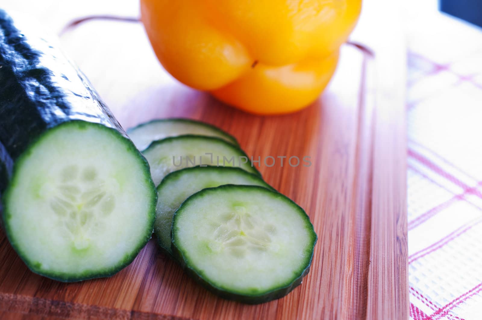 Cucumber and sweet yellow peppers on a wooden board