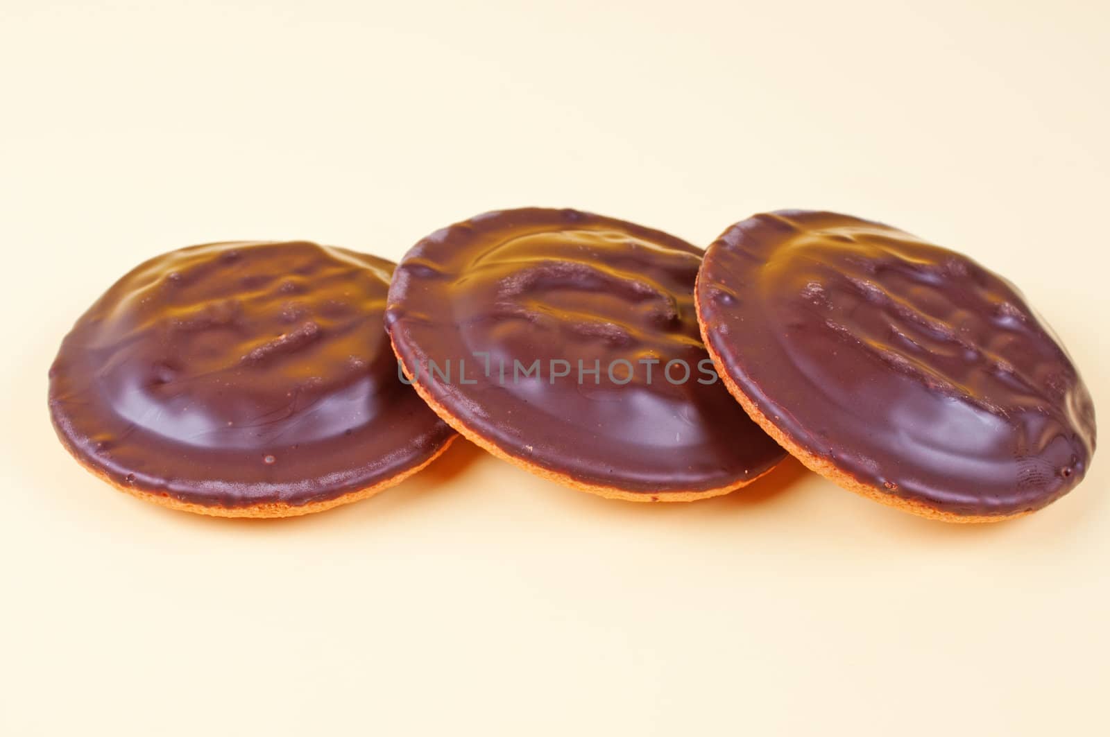 Three chocolate cookies yellow background by Nanisimova