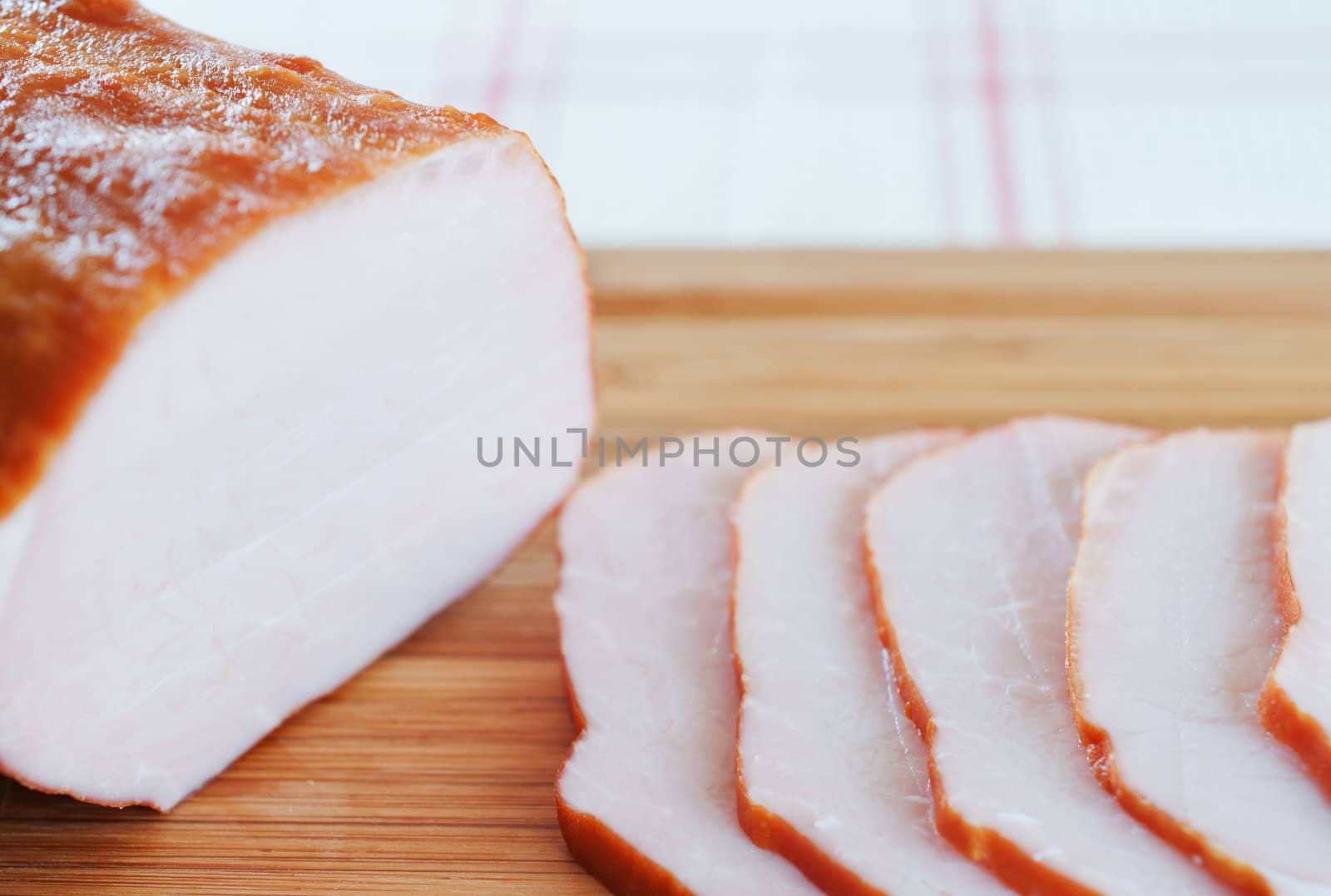 Ham cut into slices on a wooden board close up by Nanisimova