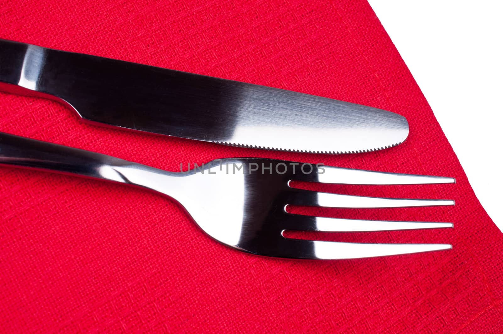 Knife and fork on red tablecloth close up