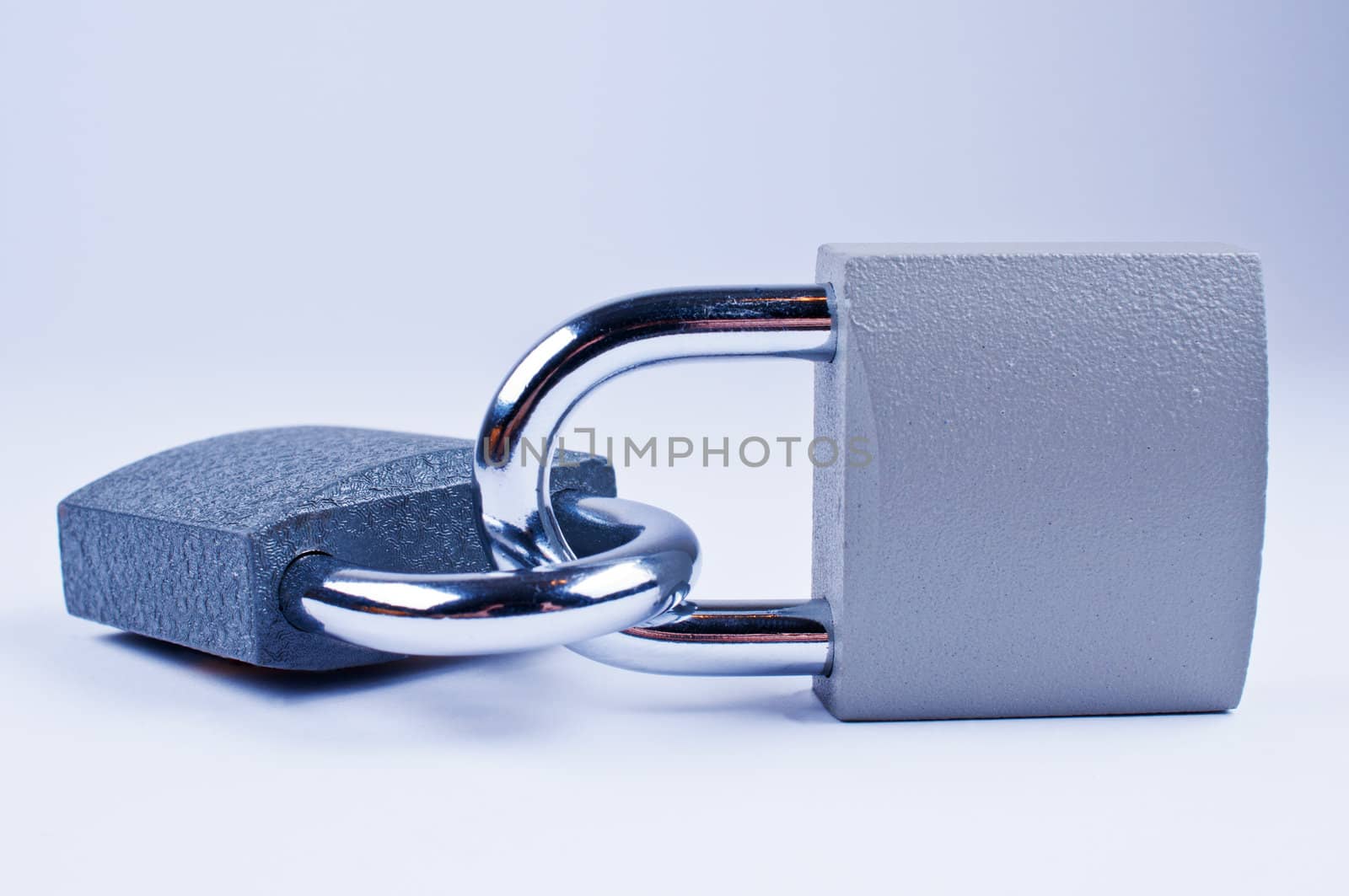 Two padlocks with a key on grey background
