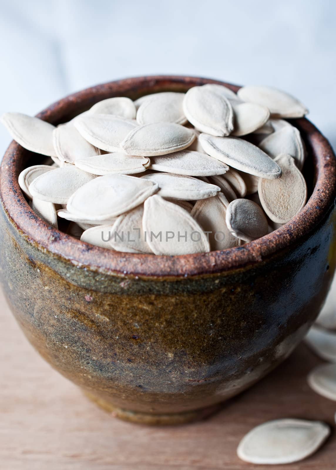 Ceramic bowl full of pumpkin seeds on kitchen table