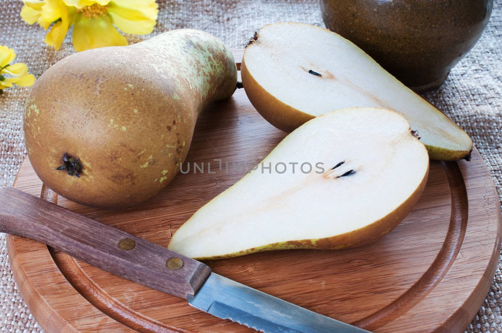 Fresh pears on cutting board with yellow flowers