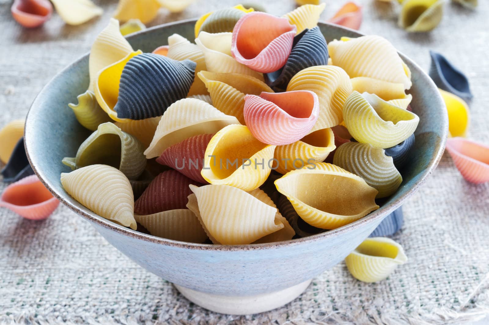 Multi colored pasta in bowl on coarse cloth by Nanisimova