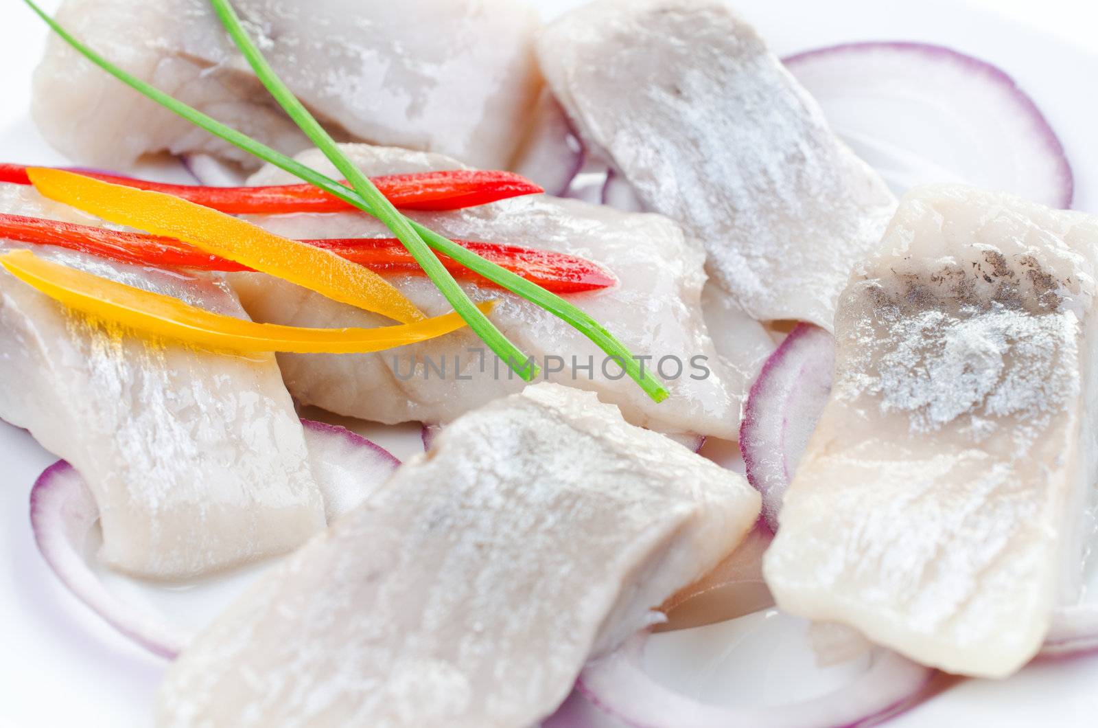 Marinated atlantic herring bites with spring onion and red and yellow pepper