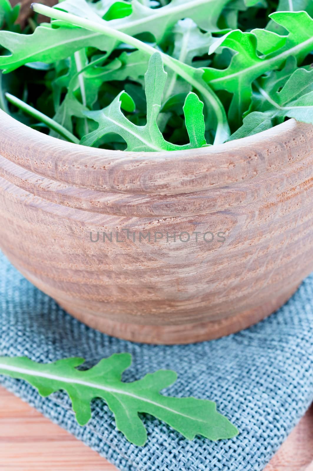 Wooden bowl with fresh rucola on table cloth