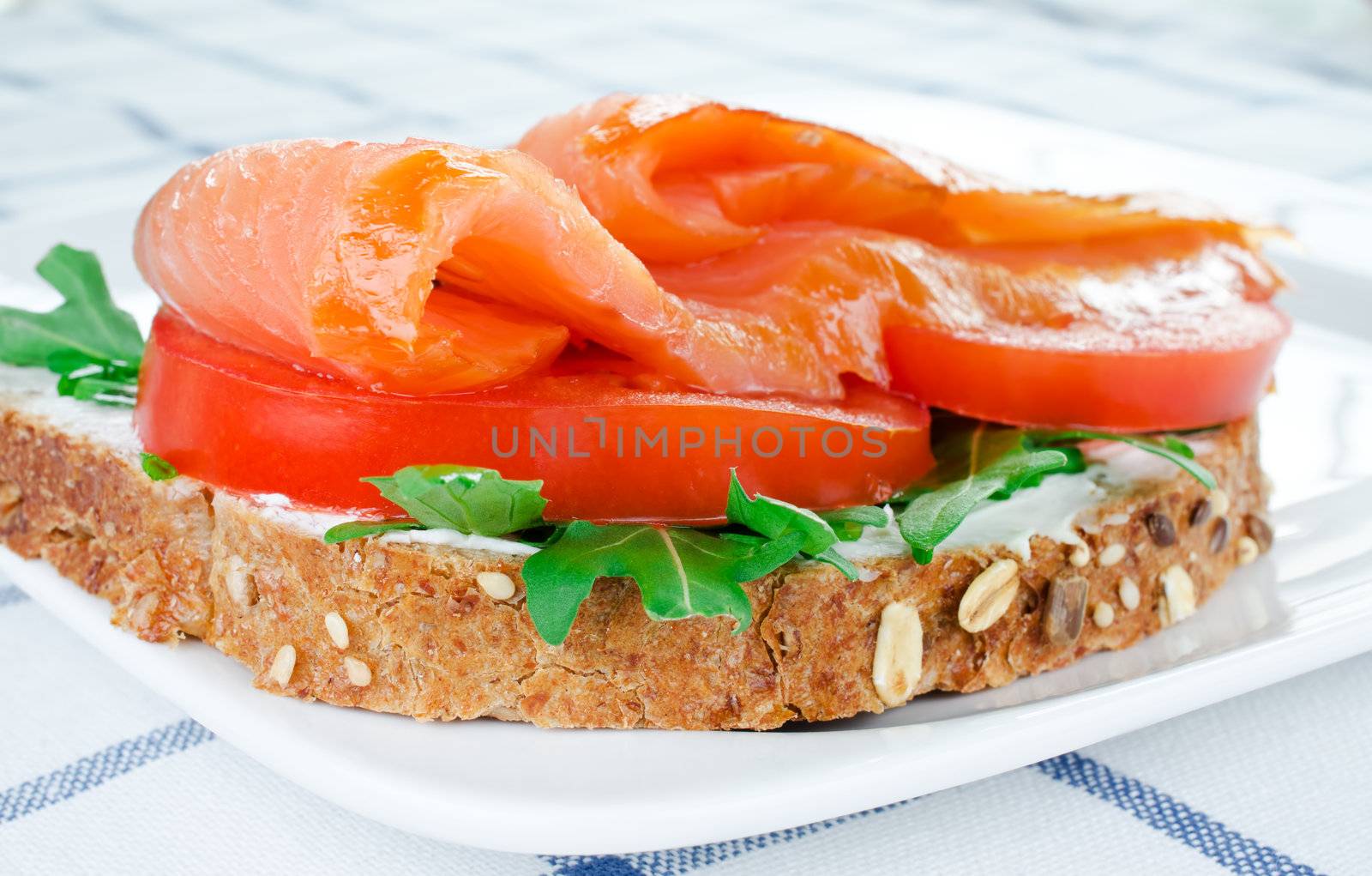 Smoked salmon sandwich with tomato, rucola, cream sandwich on rye bread