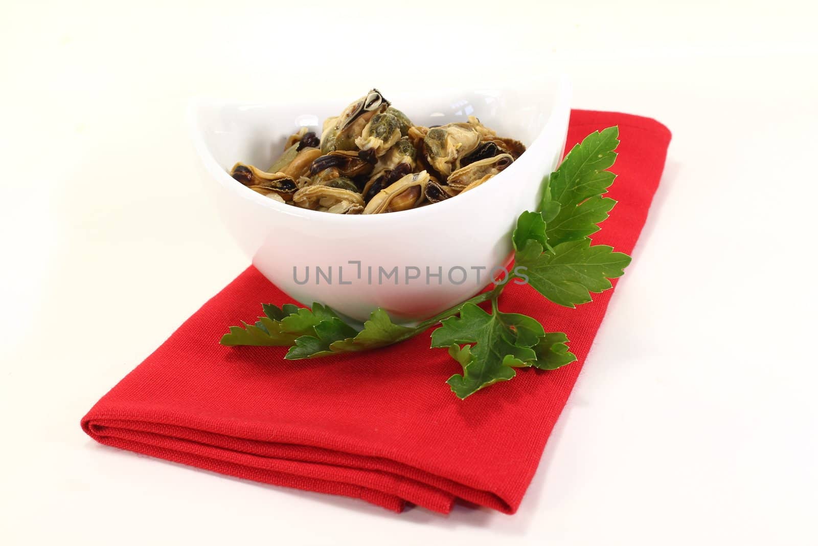 marinated mussels with flat leaf parsley in a bowl on red napkin