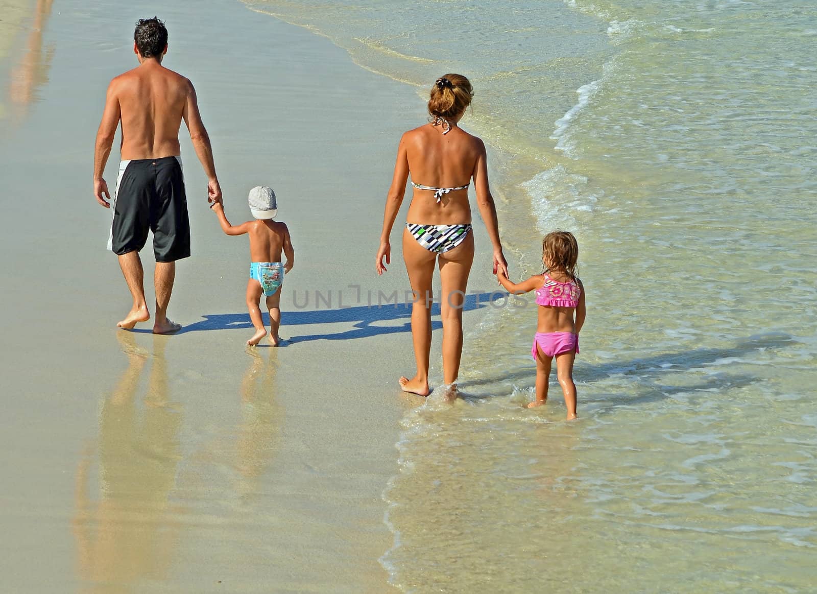 Young couple with their toddler children strolling on southeast florida beach